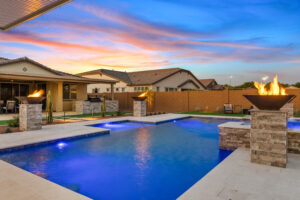 backyard pool and spa in evening with pool lighting, fire features and landscape lights.